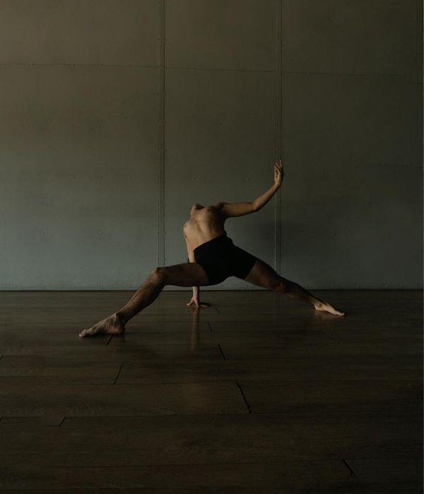 Man performing a controlled strength exercise in a minimalist dark studio.